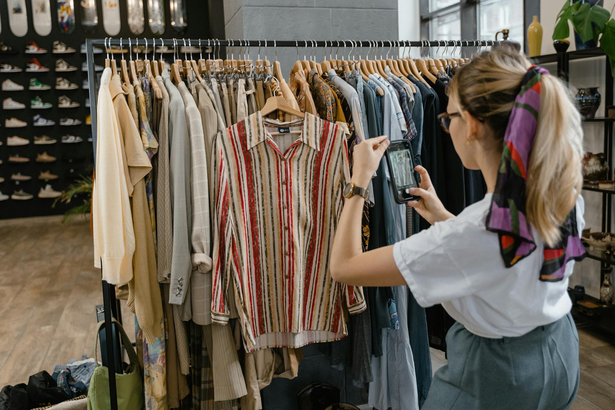 About A woman takes photos of stylish clothing in a fashionable boutique, emphasizing trendy fashion.