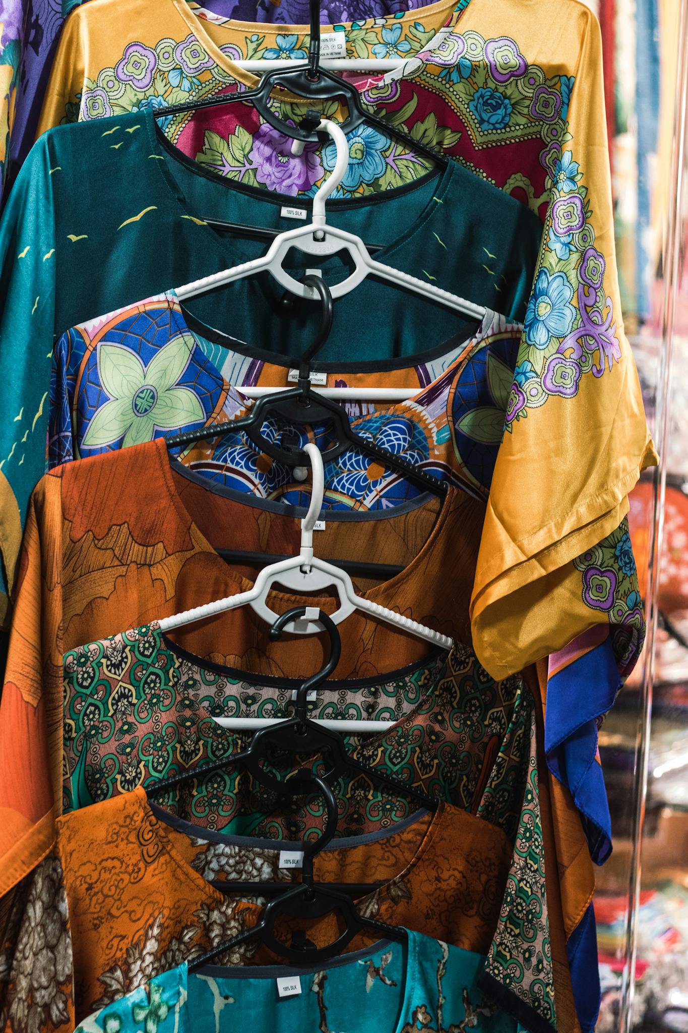Home Vibrant traditional Vietnamese garments on hangers in a Hanoi market.